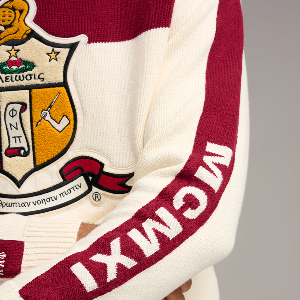 Side view of a custom knit fraternity sweater, highlighting 'MCIMXI' on the sleeve and intricate embroidery on the crest.
