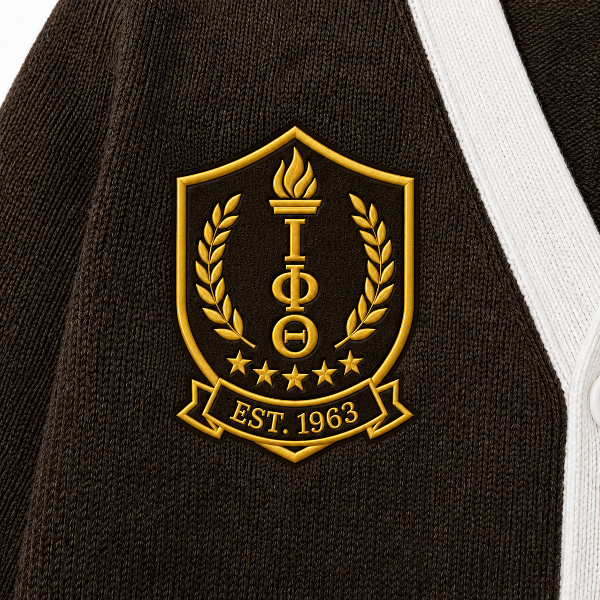 Close-up brown knit texture with ornate gold ΙΦΘ shield, 1963 detail, fine stitches and white cardigan trim