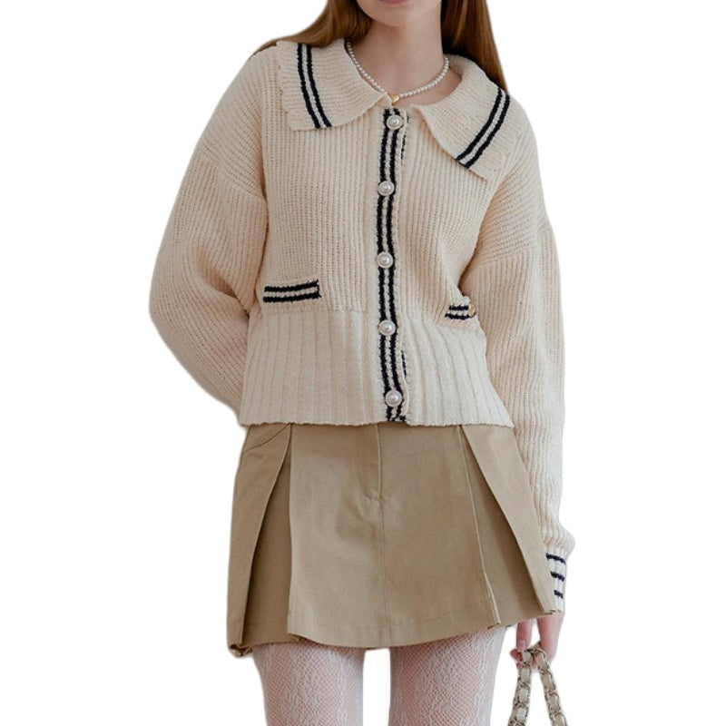 Woman wearing a custom wool blend polo collar cardigan with pearl buttons and contrasting trim