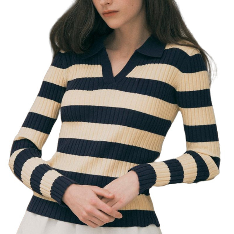 Close-up of a woman wearing a navy and beige striped wool polo sweater, highlighting the V-neck and stripe pattern.