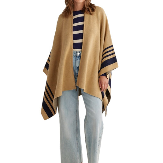 A person wearing a custom 100% cotton poncho sweater in beige with navy stripes, paired with a striped top and light blue jeans.