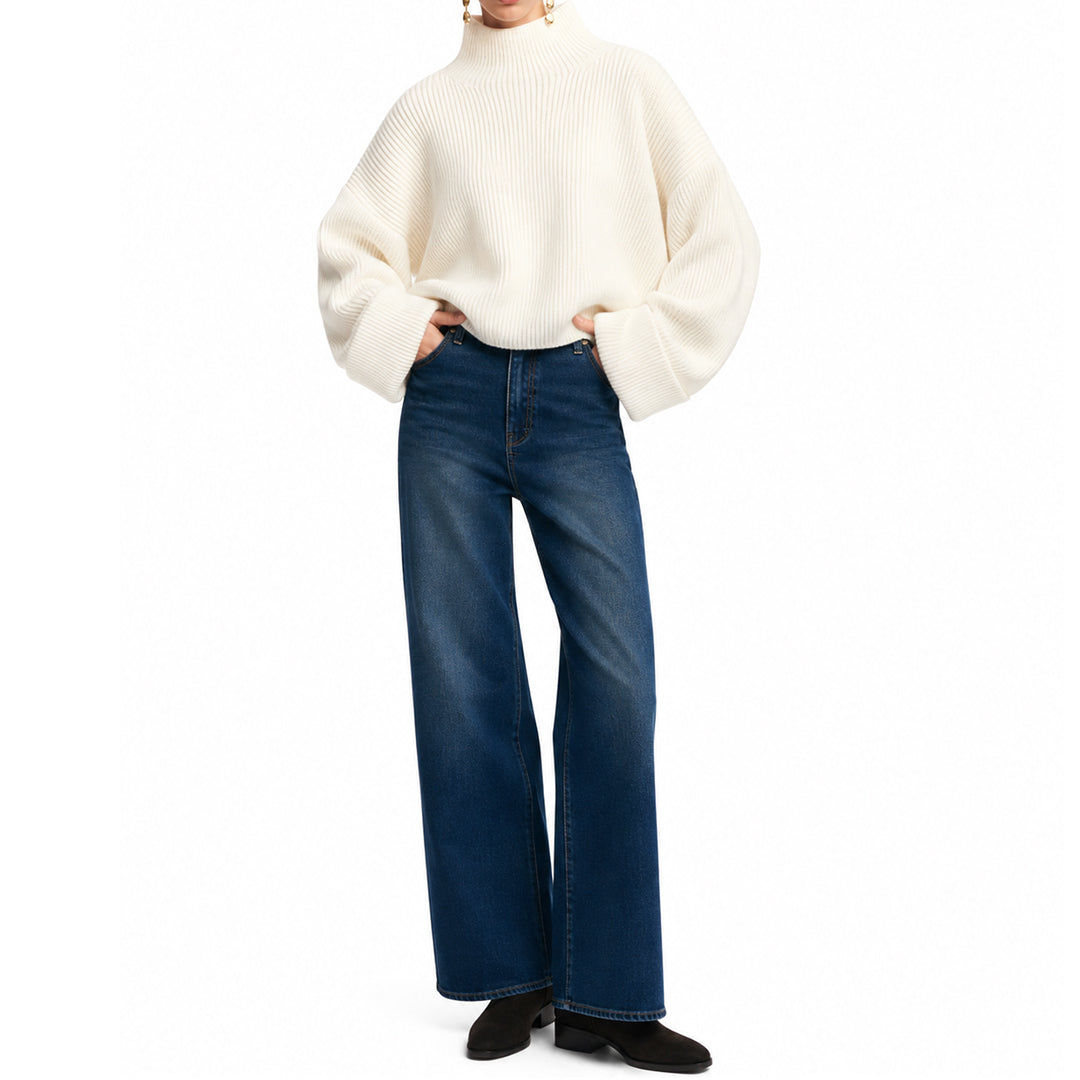 Model wearing an ivory oversized sweater with dark blue jeans.