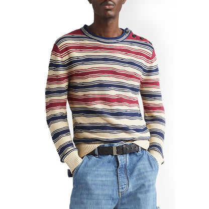 Model wearing a multi-color stripe linen knit sweater with red, navy, and cream stripes, paired with blue jeans.