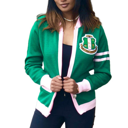 Elegant woman wearing a custom green acrylic cardigan with pink and white accents and an embroidered emblem on the chest. 