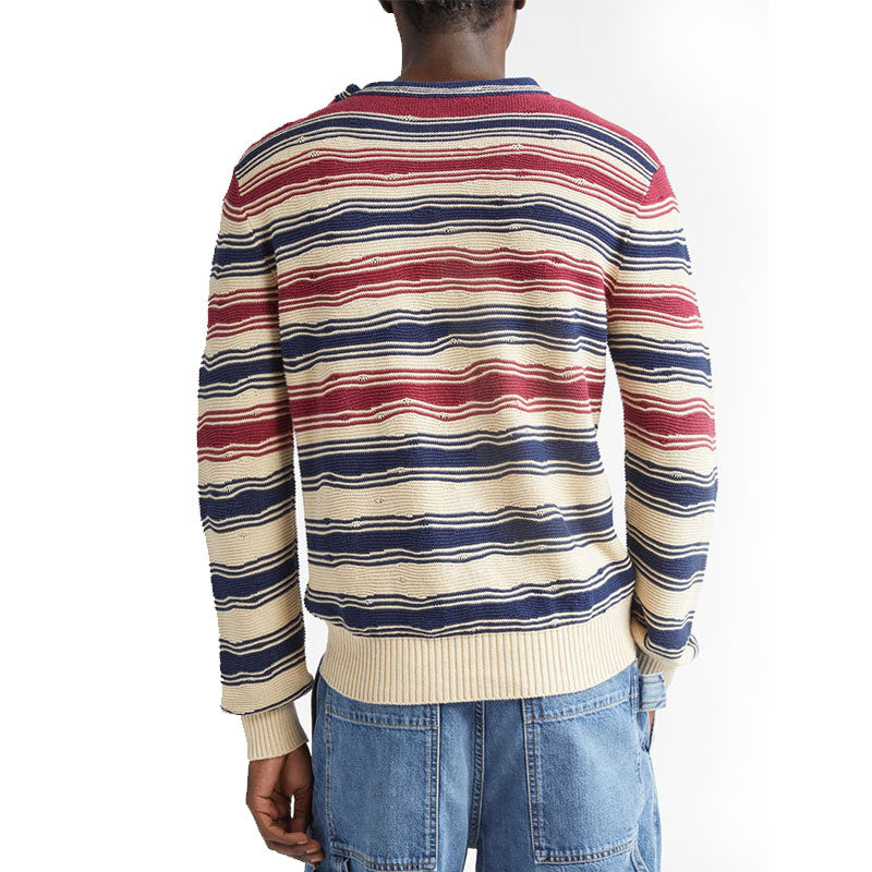 Back view of a model wearing a multi-color stripe linen knit sweater with red, navy, and cream stripes.