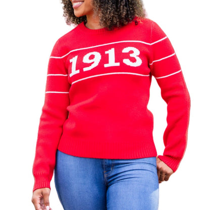 A woman smiling while wearing a vibrant red cotton sweater with '1913' in bold white numbers across the chest. The sweater is designed with additional white stripes on the sleeves, paired with blue jeans.