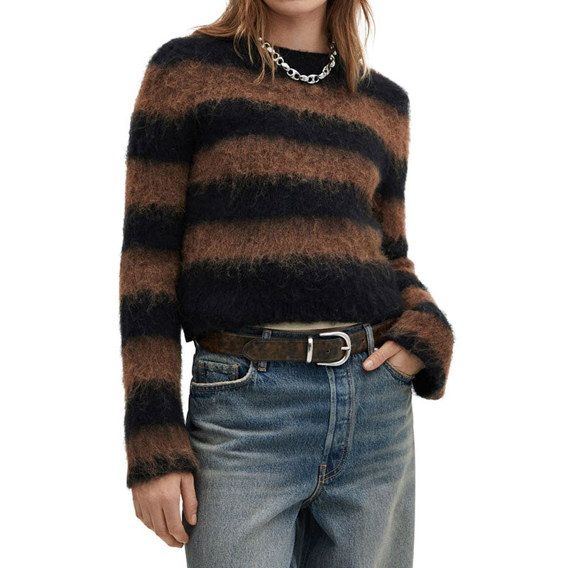 The front view of a person wearing the same fuzzy sweater with wide, horizontal black and brown stripes. The person has shoulder-length brown hair and is accessorized with a chunky silver chain necklace. They are also wearing blue jeans with a black belt, and one hand is casually placed in the front pocket.