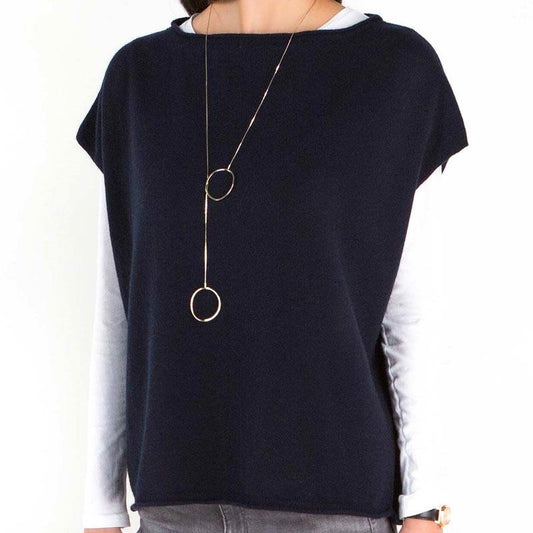 Front view of a woman wearing a custom crew neck 100% wool knitted sweater in navy blue over a long-sleeve white top, accessorized with a long gold necklace.