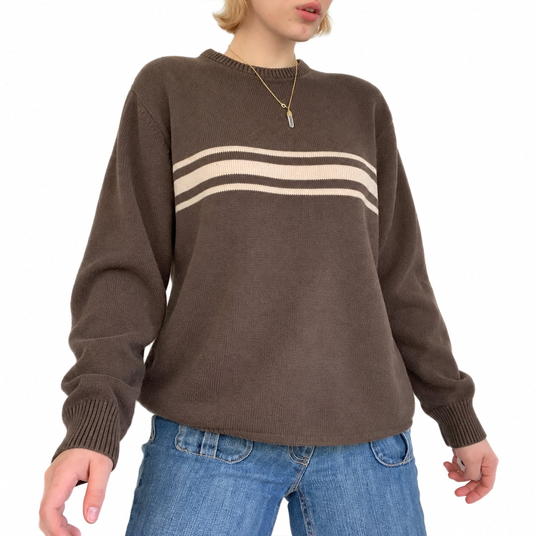 Woman wearing a brown knit pullover with cream horizontal chest stripes.