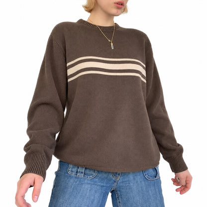 Woman wearing a brown knit pullover with cream horizontal chest stripes.