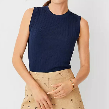 Front view of a woman wearing a navy blue custom round neck women’s tank top knitted sweater paired with beige eyelet skirt.