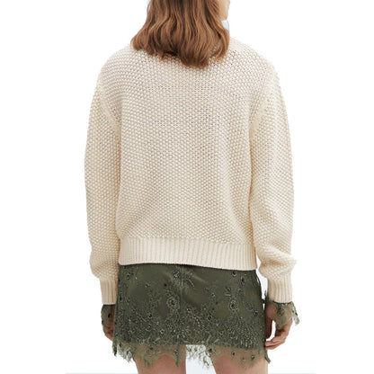 Back view of a cream-colored, grid pullover sweater worn by a model with a green lace skirt. The sweater features a textured knit pattern and ribbed hem.