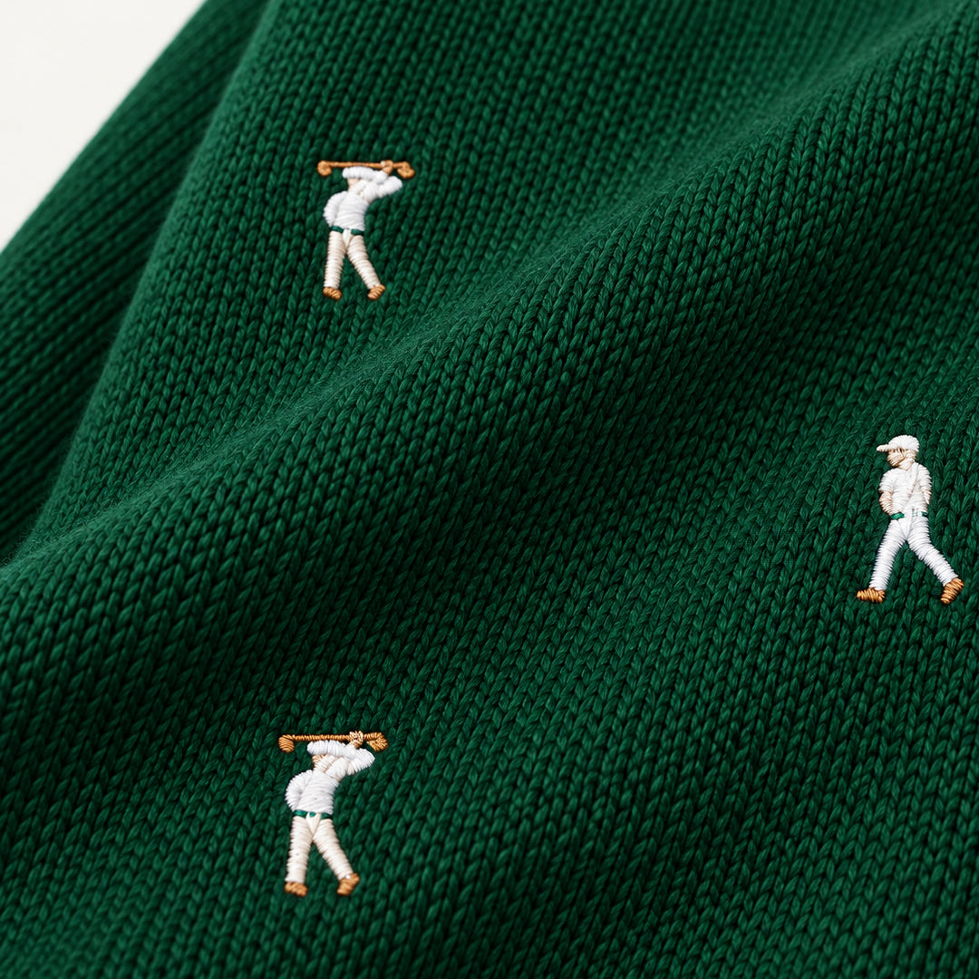 Close-up of embroidered golfer motifs on dark green textured knitwear
