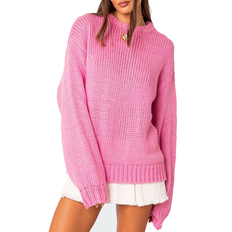 Front view of a woman wearing a pink knit sweater with a round neckline and ribbed cuffs and hem.