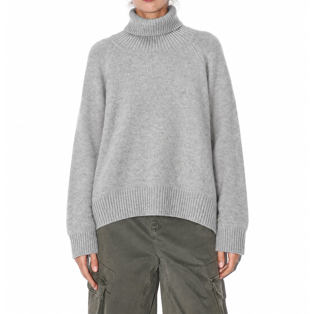 Woman wearing a grey high-neck knit pullover with dark trousers, front view.