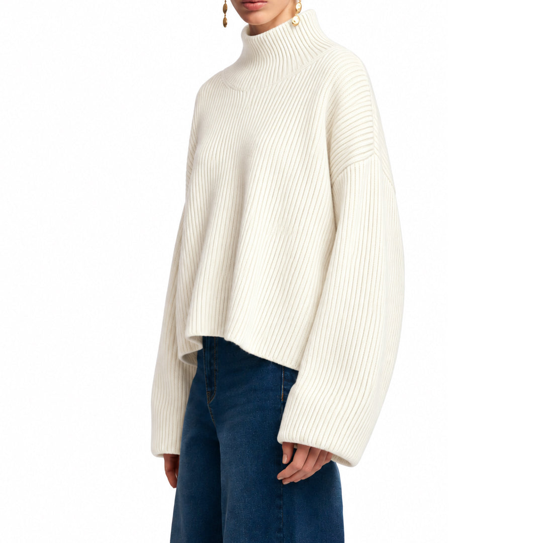 Side view of an ivory oversized knit pullover with dropped shoulders.