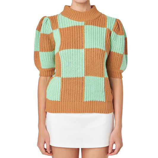 Front view of a woman wearing a cotton blend knit pullover sweater with a brown and mint green checkerboard design.