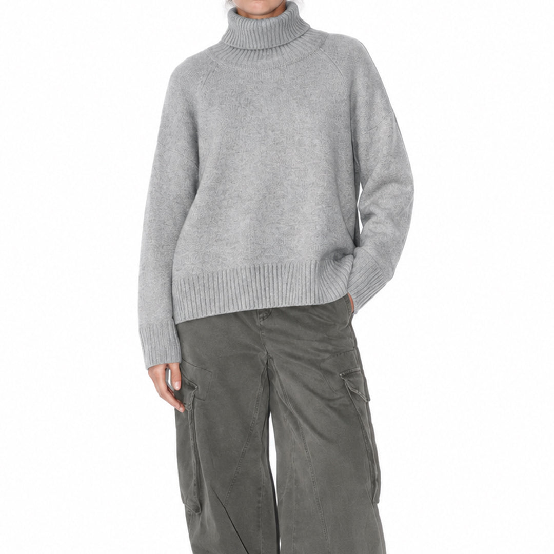 Side view of a woman wearing a relaxed-fit grey turtleneck sweater.