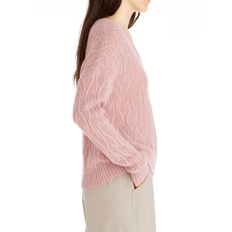 Side view of a model wearing a pink custom wool blend cable knit sweater.