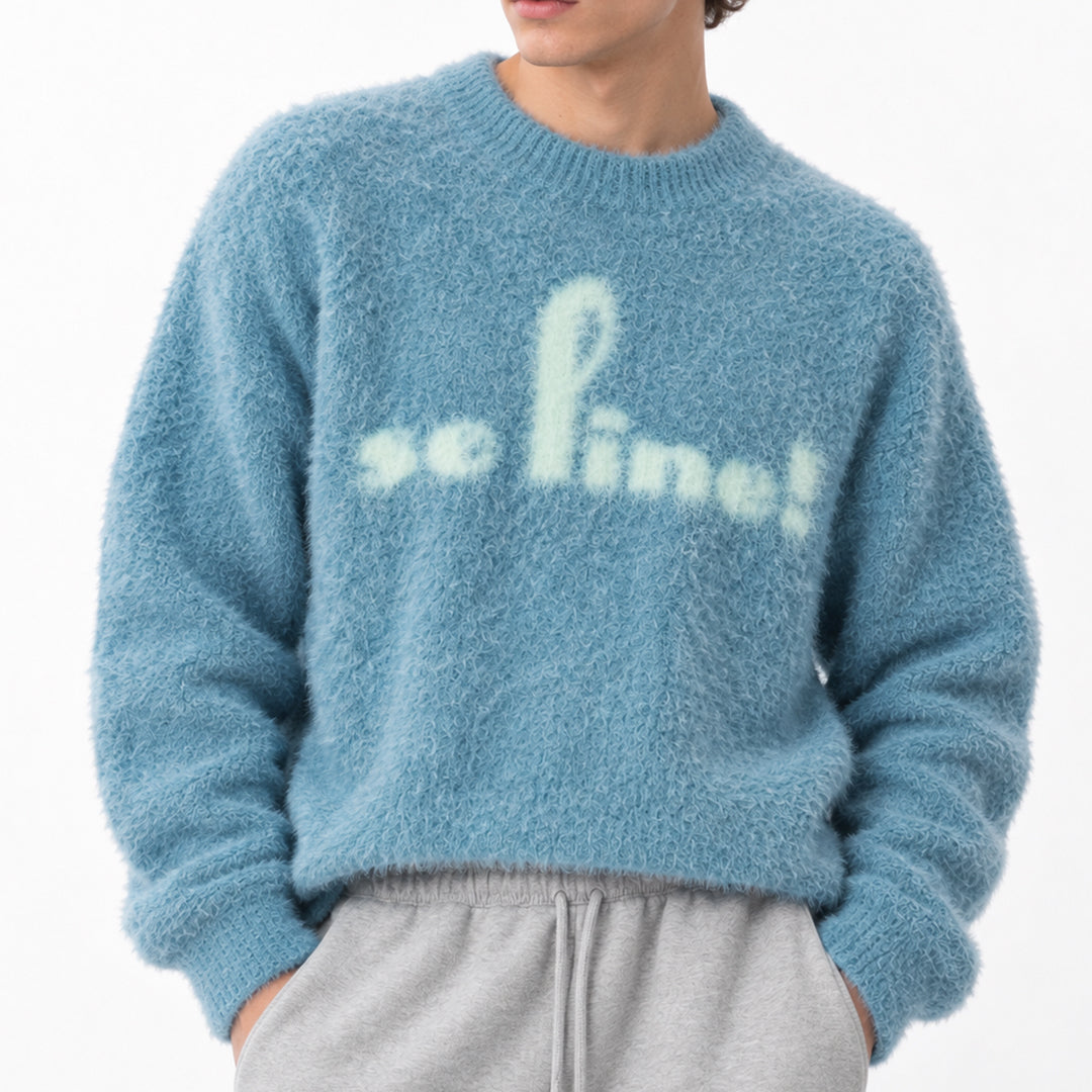Blue graphic sweater with cream slogan lettering, front styling.