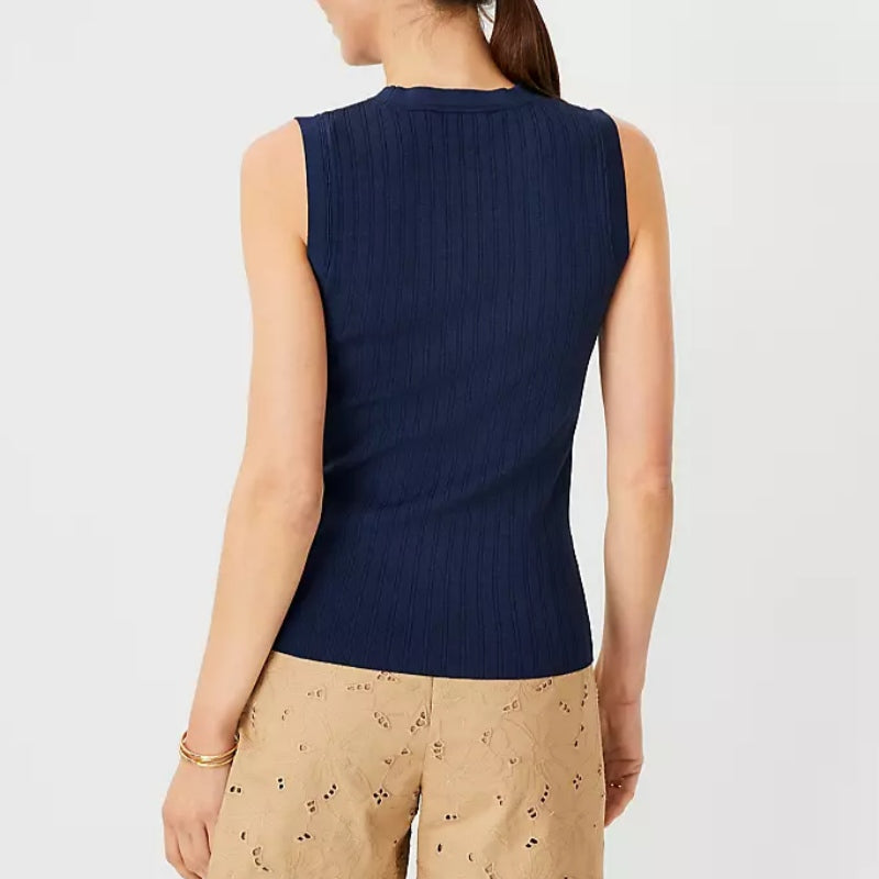 Back view of a woman wearing a navy blue custom round neck women’s tank top knitted sweater paired with beige eyelet skirt.