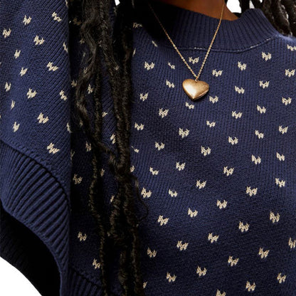 Close-up view of a navy blue knit sweater with a delicate butterfly pattern, highlighting the textured fabric and intricate design.