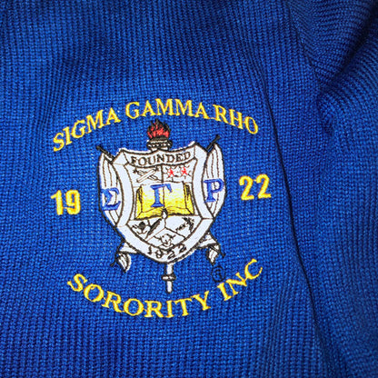 Close-up of Sigma Gamma Rho Sorority crest embroidery on blue cardigan