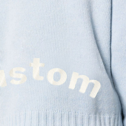 Close-up view of a custom light blue knit sweater with visible "custom" text, ideal for OEM/ODM manufacturing.