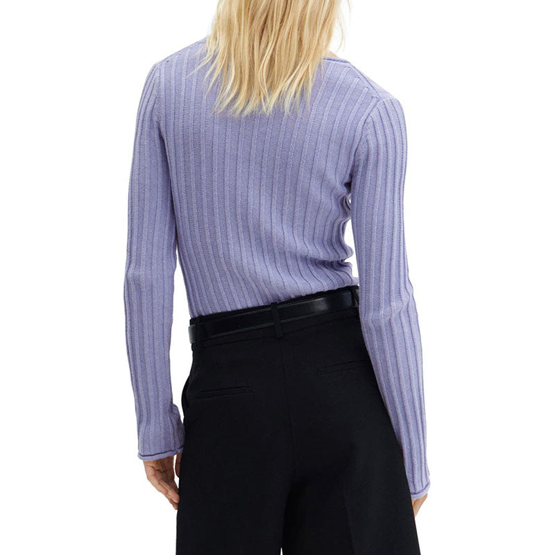 Back view of a woman wearing a light purple ribbed knit sweater made from a premium wool blend, paired with black trousers.