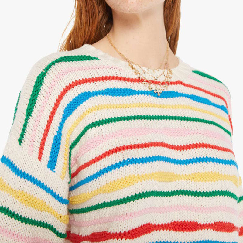 Close-up view of the rainbow striped sweater, focusing on the upper half. The vibrant colors of the stripes are clearly visible, and the person is wearing a gold necklace. This close-up highlights the texture and knit pattern of the sweater.