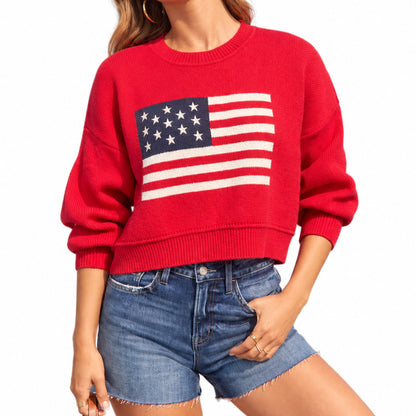 Red American flag sweater with long sleeves and bold chest print, seated model view