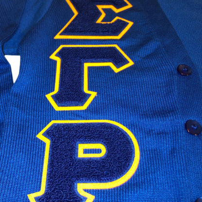 Close-up of blue cardigan with yellow Greek letters "ΣΓΡ"