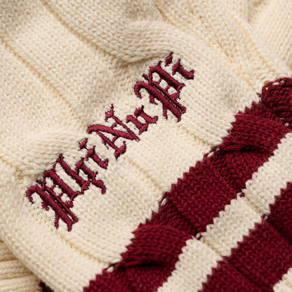 Close-up of "Phi Nu Pi" embroidery on cream cable knit sweater