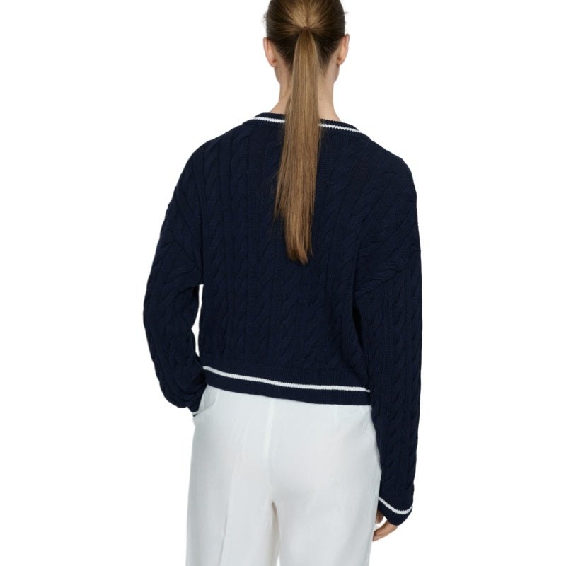 Rear view of a person wearing a dark blue cable knit cardigan with white trim, showcasing the back design.