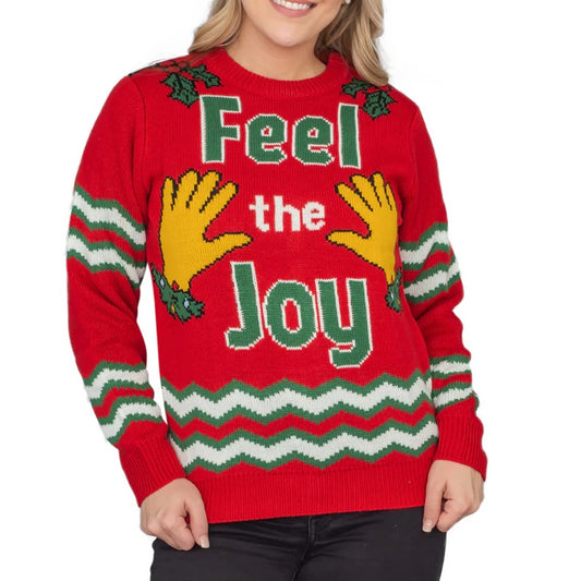 Red Christmas sweater with 'Feel the Joy' design, worn by a woman, featuring yellow hands and festive holly accents.