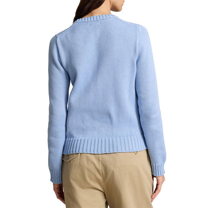 Woman wearing a light blue knit sweater with an American flag pattern on the chest. The sweater features a crewneck, long sleeves, and ribbed cuffs and hem.