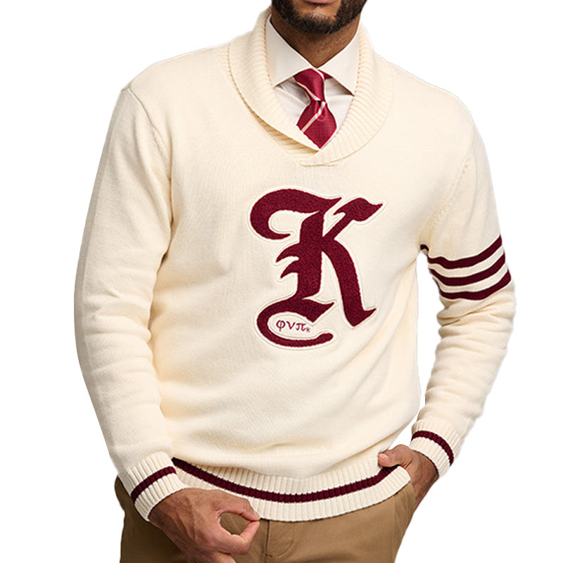 A man wearing a cream-colored custom fraternity sweater with maroon stripes on the sleeves and the text 'K' on the front, paired with a red tie.