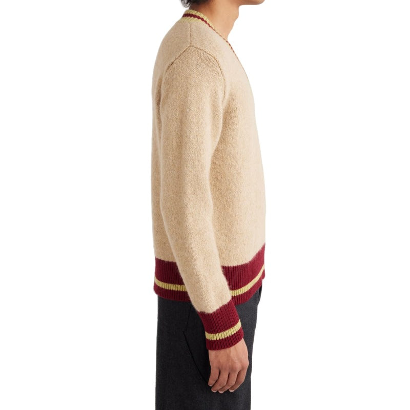 Side view of a man in a beige merino wool V-neck sweater featuring burgundy and gold stripes on the ribbed cuffs and waistband. The image highlights the sweater's premium knit and fit, suitable for custom sweater wholesale.