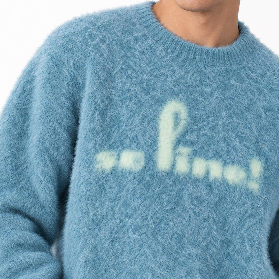 Close-up of cream script lettering on a blue knit sweater.