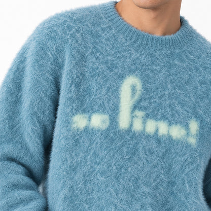 Close-up of cream script lettering on a blue knit sweater.