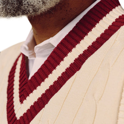 Close-up of cream cable knit vest with maroon V-neck trim