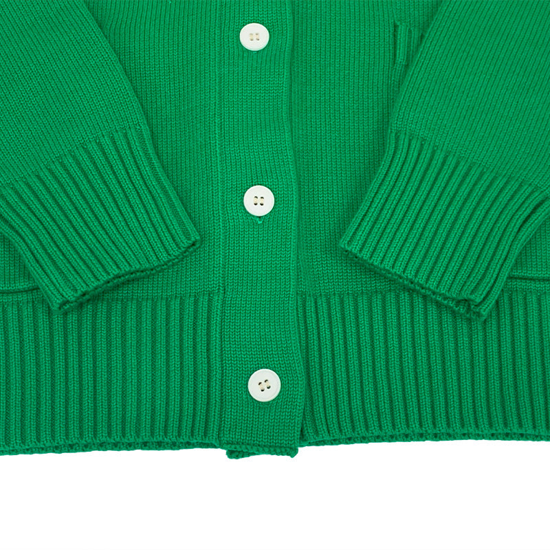 Detail of ribbed cuffs and white buttons on green cardigan – crafted by experienced cardigan manufacturer.