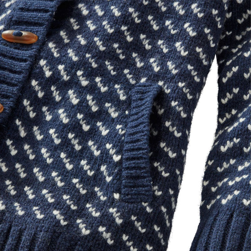 Detailed view of the pocket and button closure on a navy blue wool blend knit cardigan sweater with white pattern.