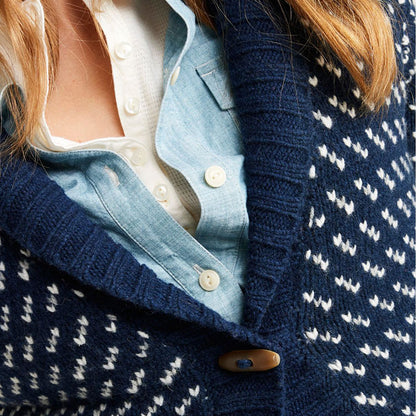 Close-up view of the shawl collar and buttons on a navy blue wool blend knit cardigan sweater worn over a white and blue shirt.