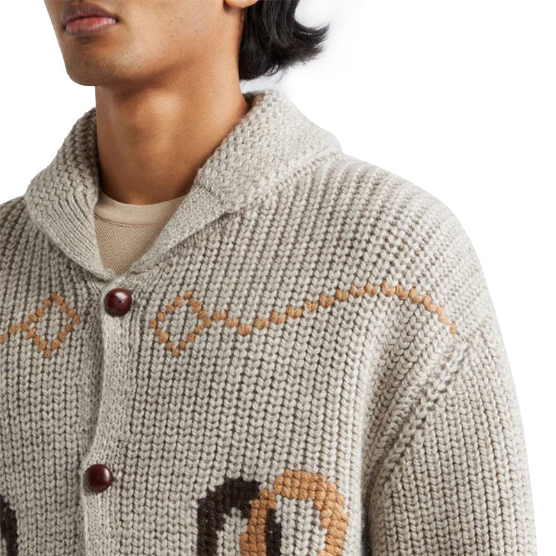 Close-up of a beige wool blend knit sweater with turndown collar and detailed knitting.