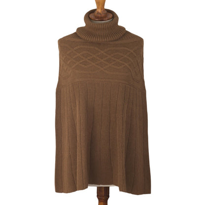 Brown 100% cotton knit poncho displayed on a mannequin, featuring a cozy turtleneck and detailed with an intricate cable knit pattern on the upper part and vertical ribbing on the lower half.