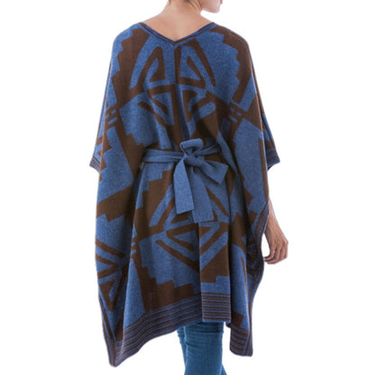 A person modeling a custom 100% acrylic poncho sweater with blue and brown geometric patterns, showcasing the V-neck design and waist belt for a fashionable look.