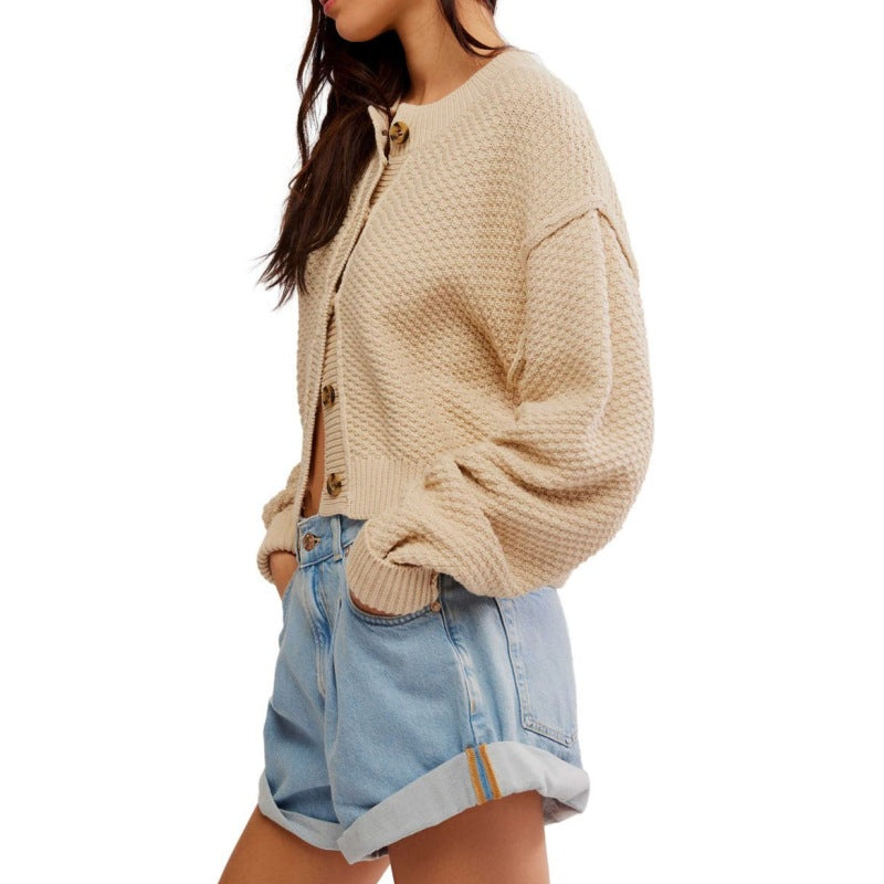 Detailed side view of the knit texture and construction of a beige cardigan, highlighting its oversized sleeves and cozy fit.