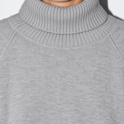 Detail of the ribbed high neckline on a grey knit sweater.