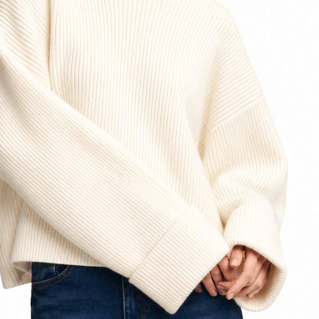 Close-up of the ivory sweater's knit texture and ribbed cuff.